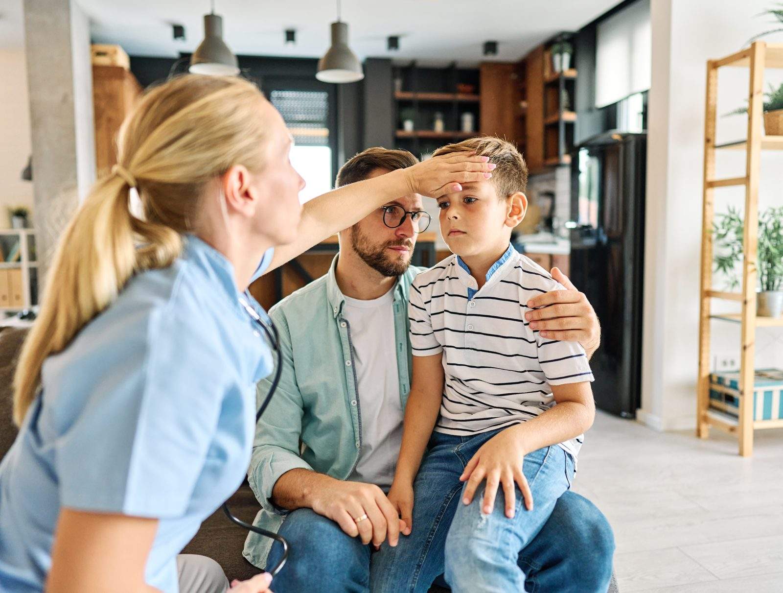 A nurse checking a school-age boy while his father sits with him