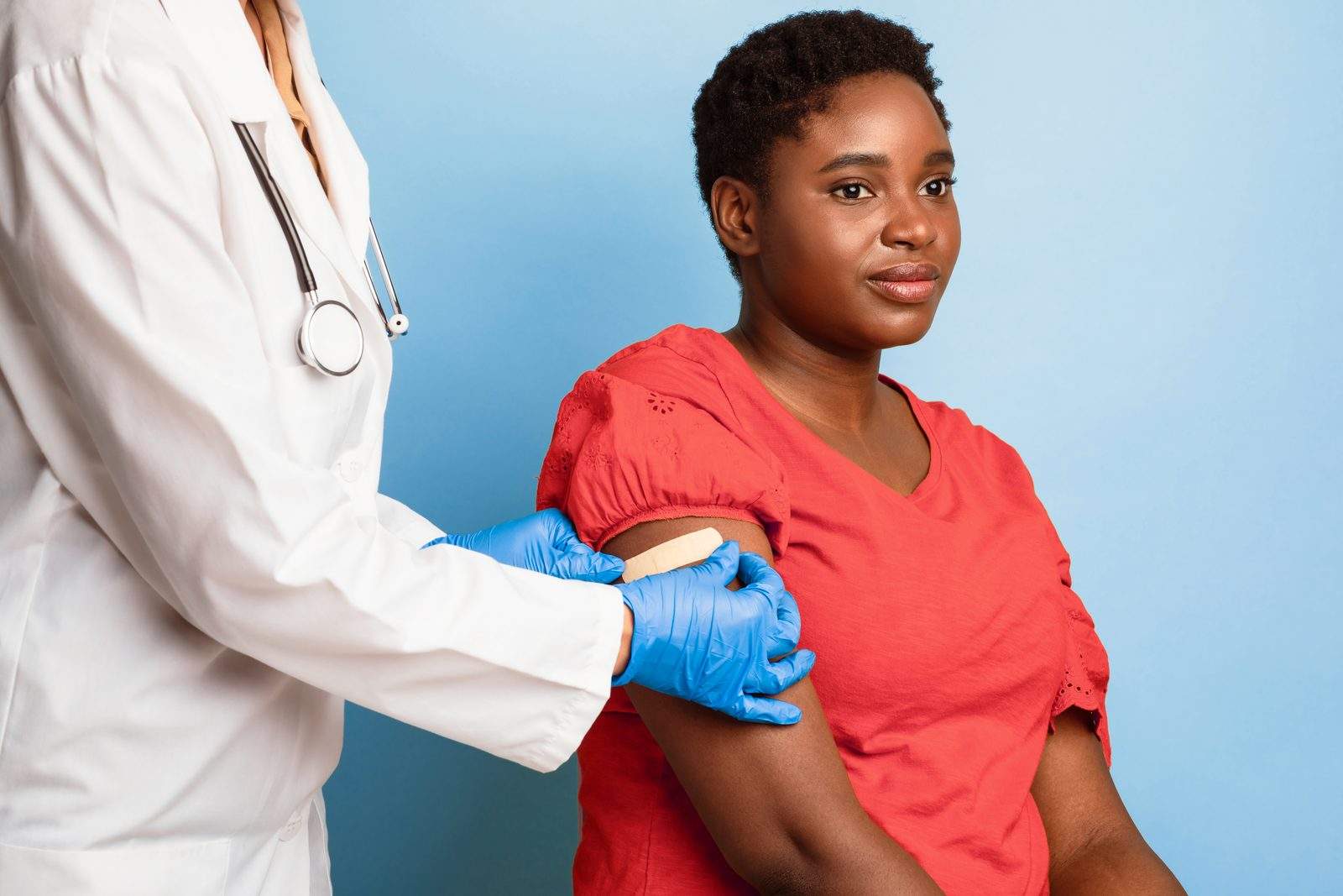 A provider smoothing a bandage onto a patient's arm after a vaccination