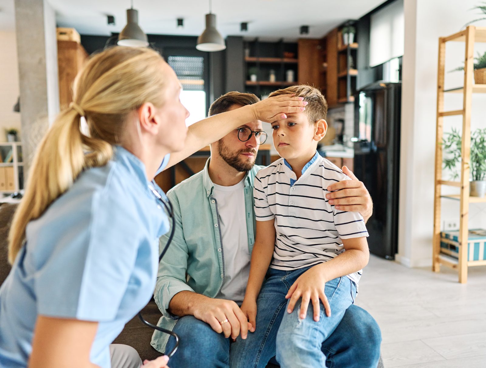 A nurse checking a school-age boy while his father sits with him