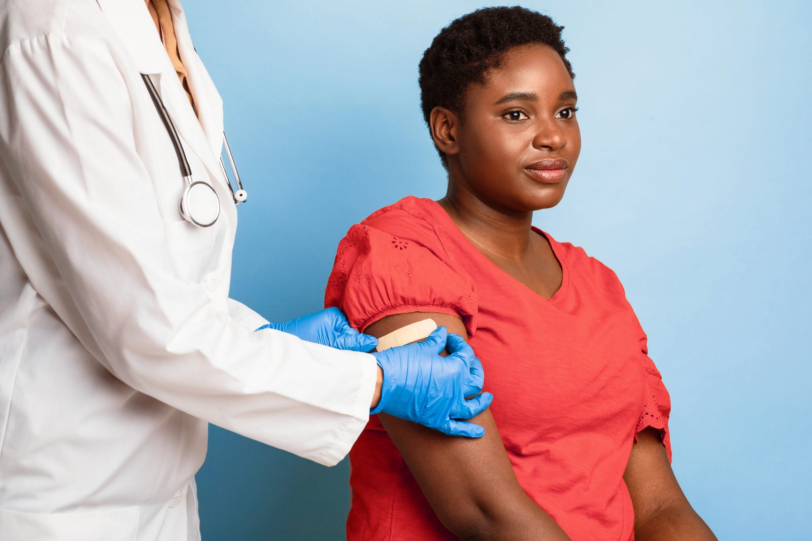 A provider smoothing a bandage onto a patient's arm after a vaccination